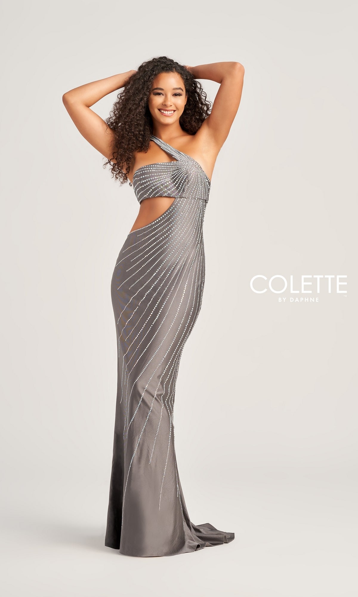 A woman poses with her hands above her head, wearing the Colette One-Shoulder Sleek Long Prom Dress CL5139—a fitted silver beaded gown with diagonal sparkly lines, cutouts, and asymmetrical style for glamorous flair.